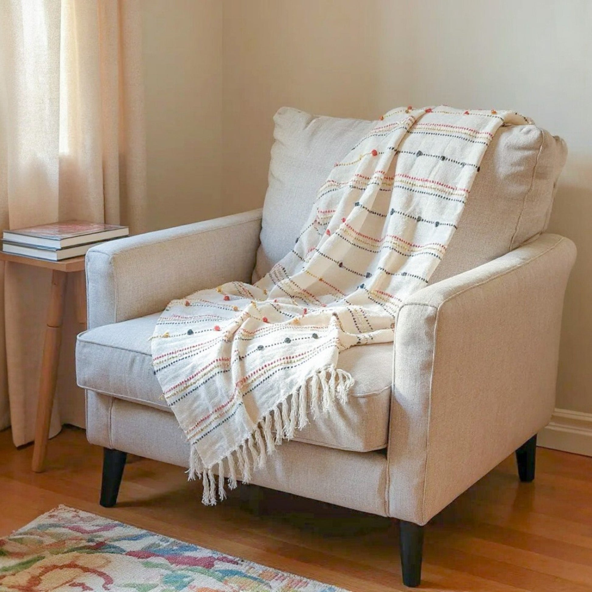 Beige armchair with a plaid blanket draped over it in a cozy living room setting.