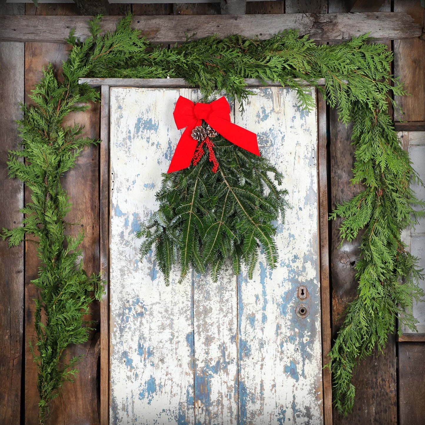 Decorative wreath with a red bow on a rustic wooden door